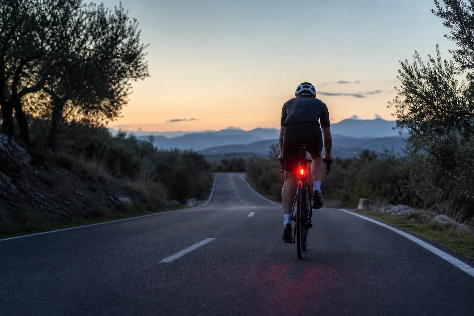 Cyclist riding at dusk with tail light visible from behind