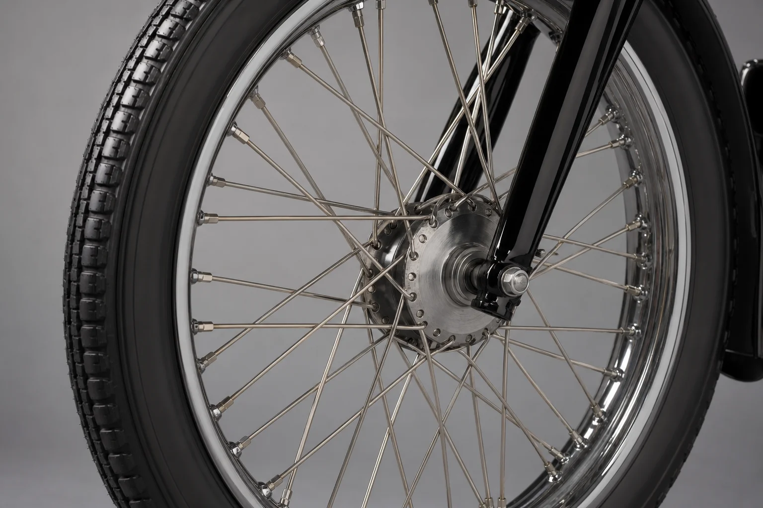 Close-up of motorcycle spoked wheel with tube tire on neutral background