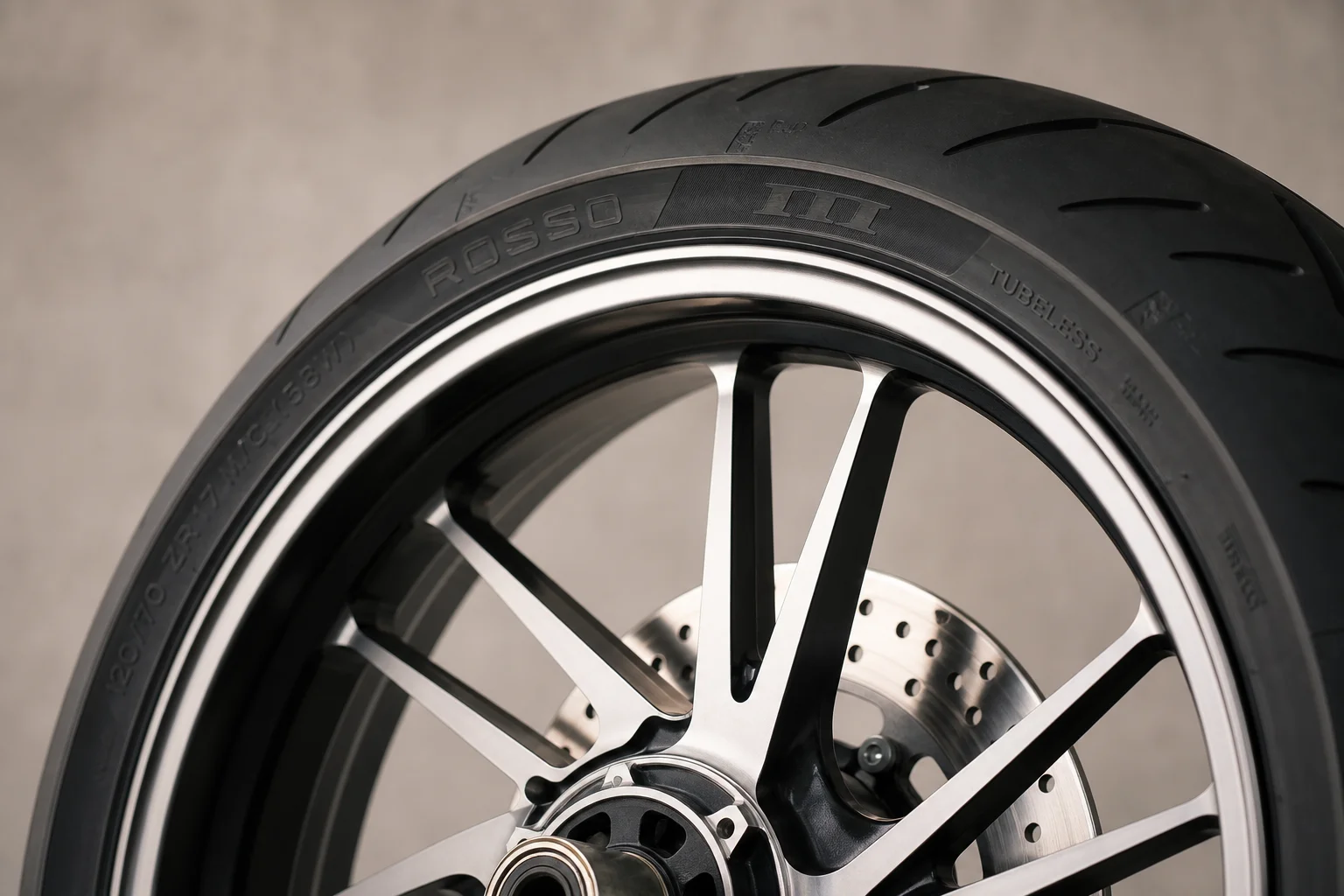 Motorcycle alloy rim with tubeless tire mounted, polished finish detail