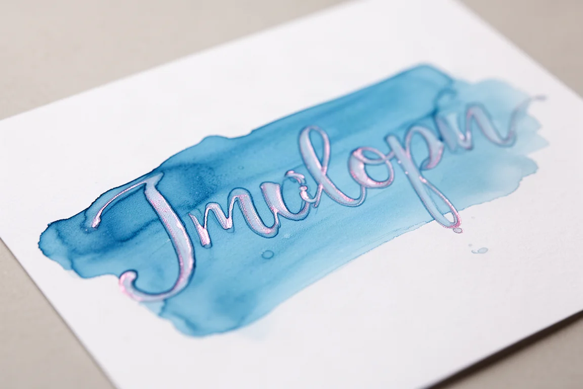 Bright light blue ink swatch drying on white paper with a faint pink sheen at the edges
