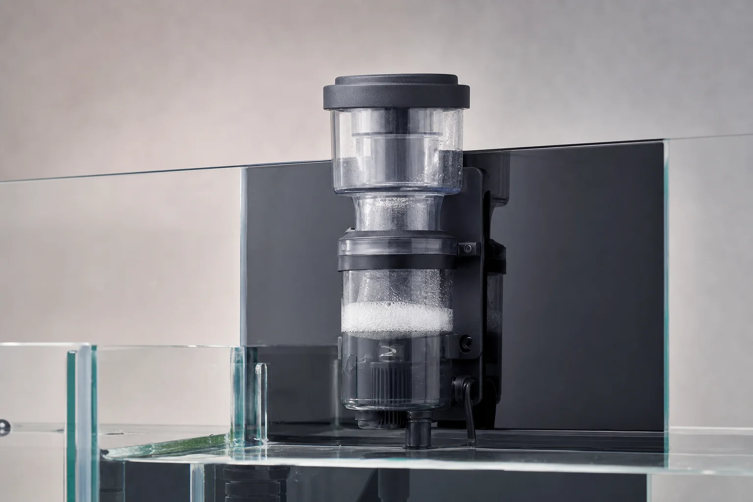 Protein skimmer mounted in aquarium back chamber against glass