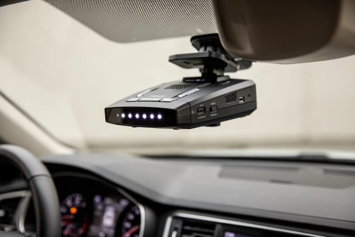 Radar detector mounted on a car windshield with LED indicators glowing