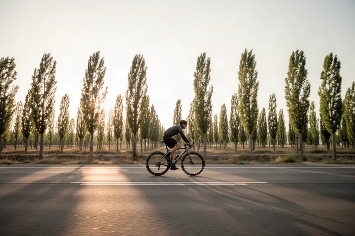 Radfahrer fährt bei niedrigem goldenen Licht mit hoher Geschwindigkeit über eine flache Straße