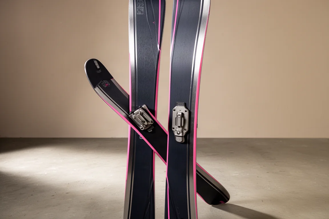 Pair of frontside carving skis with metal laminates and pink sidewalls on concrete