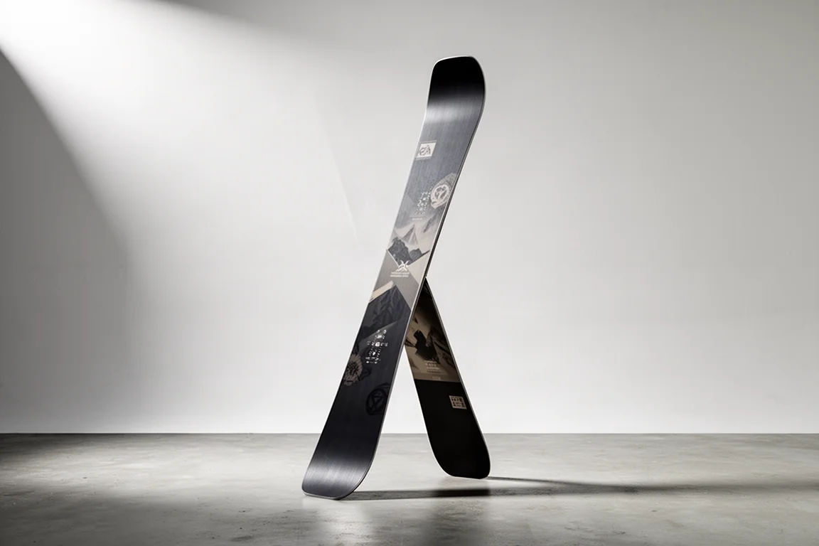 Wide freeride twin tip ski standing upright on a concrete surface against a neutral backdrop