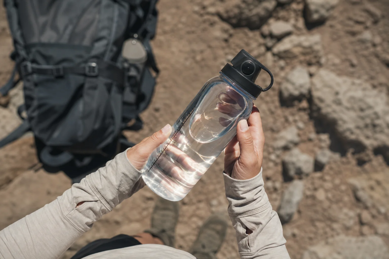 Hiker's hands holding water bottle checking hydration level