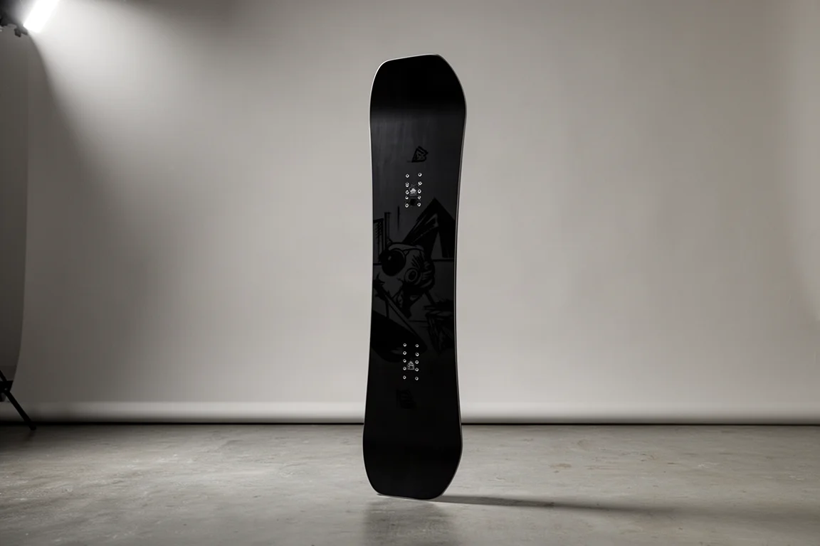 Czarny snowboard Weston Hatchet stojący pionowo na neutralnym szarym tle