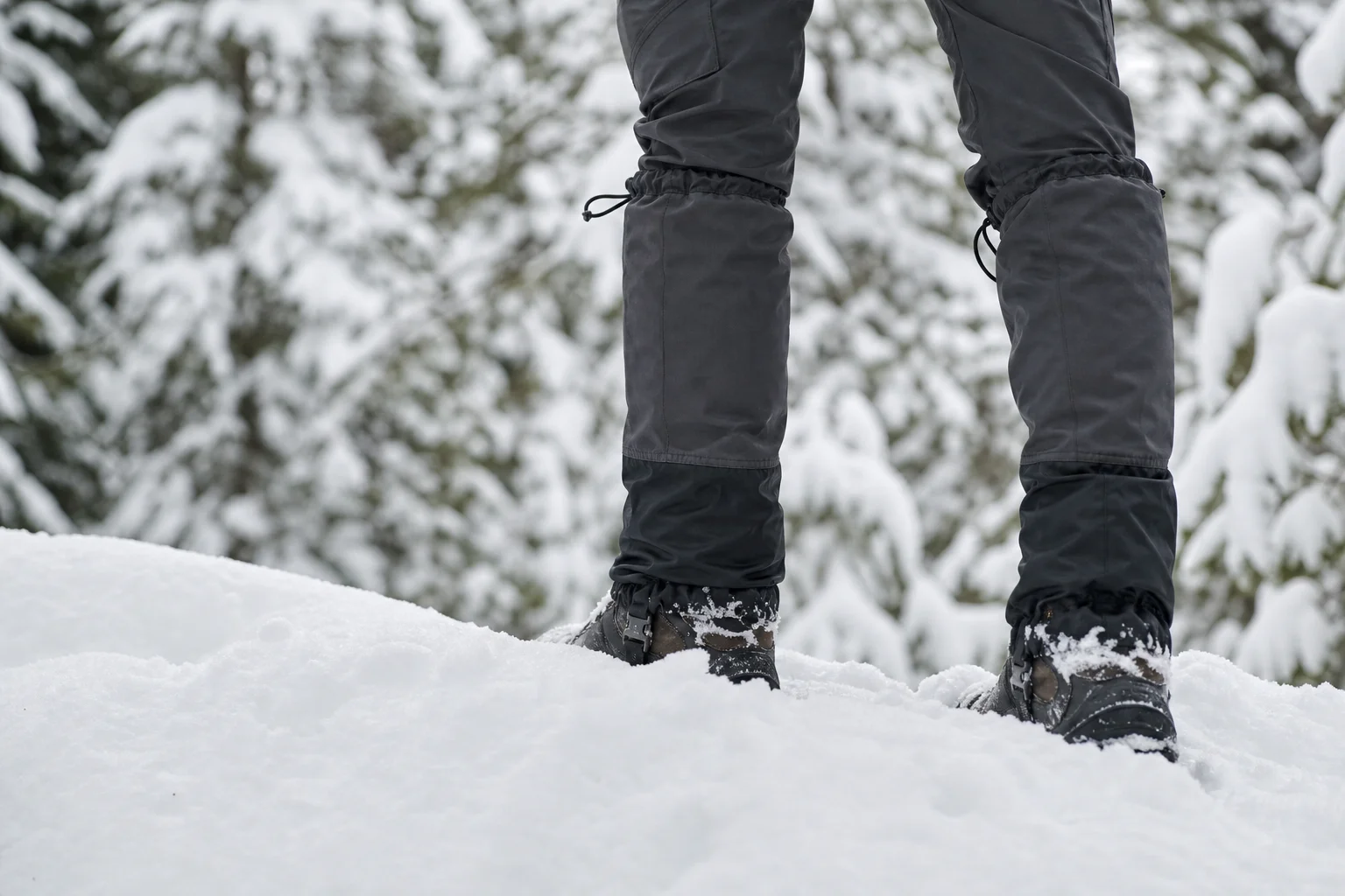 Hiker's lower legs showing gaiters sealed over boots and pants in snowy terrain