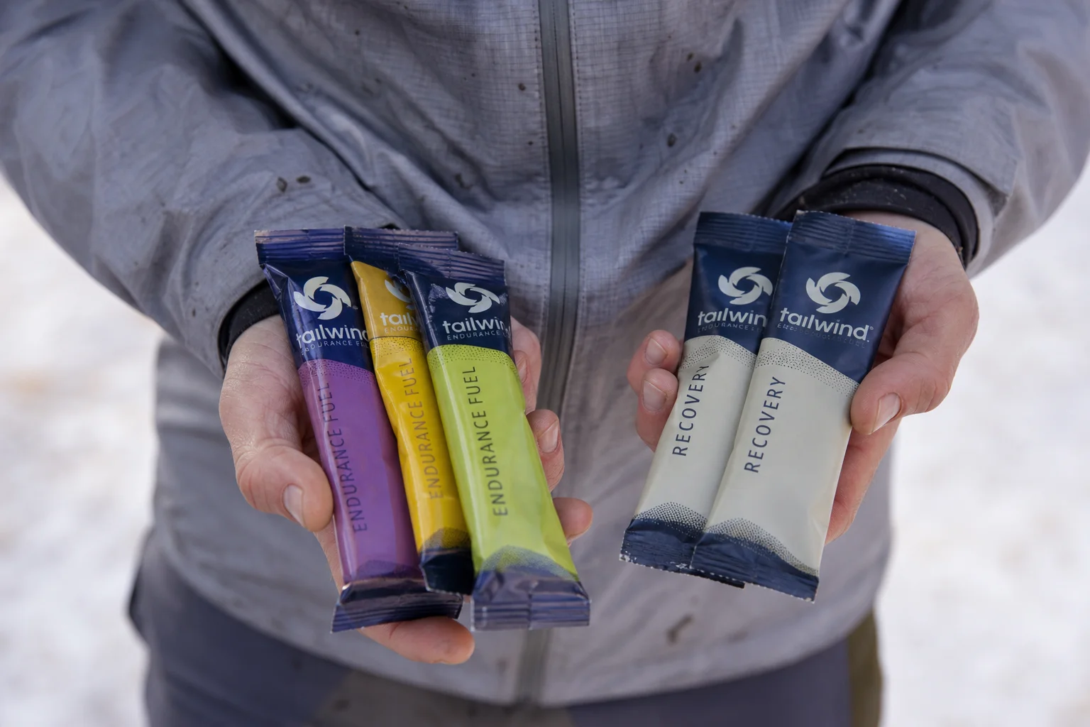 Mains d'un coureur tenant des sachets de nutrition et de récupération Tailwind après une sortie