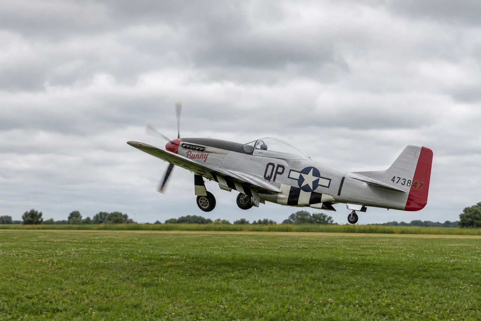 RC-Flugzeug beim Start von einer Graspiste unter bewölktem Himmel