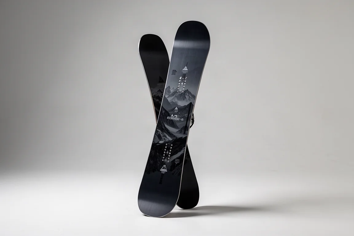 Directional freeride snowboard standing upright on a neutral grey studio backdrop