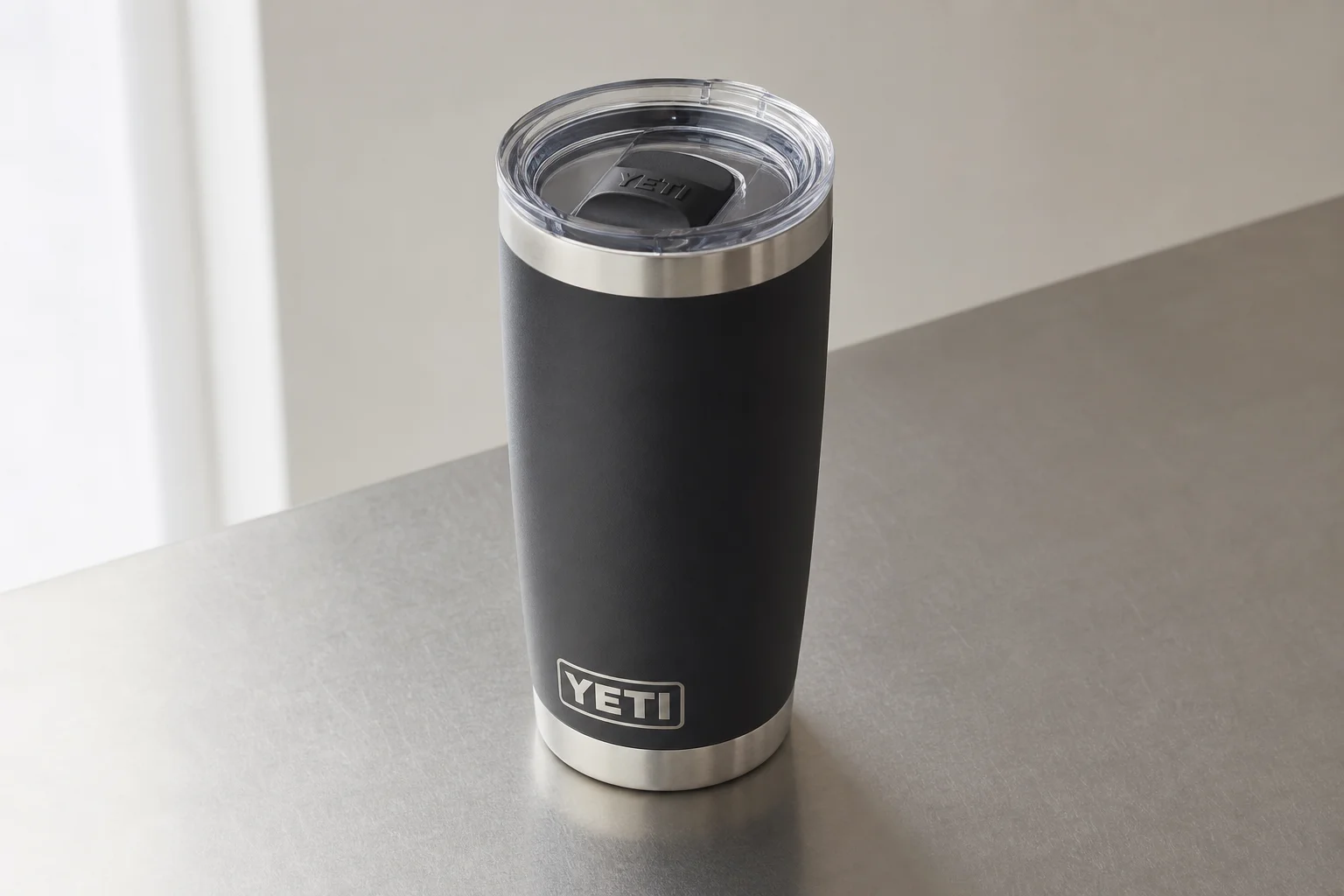 Nine insulated travel mugs arranged on concrete surface in various styles and colors