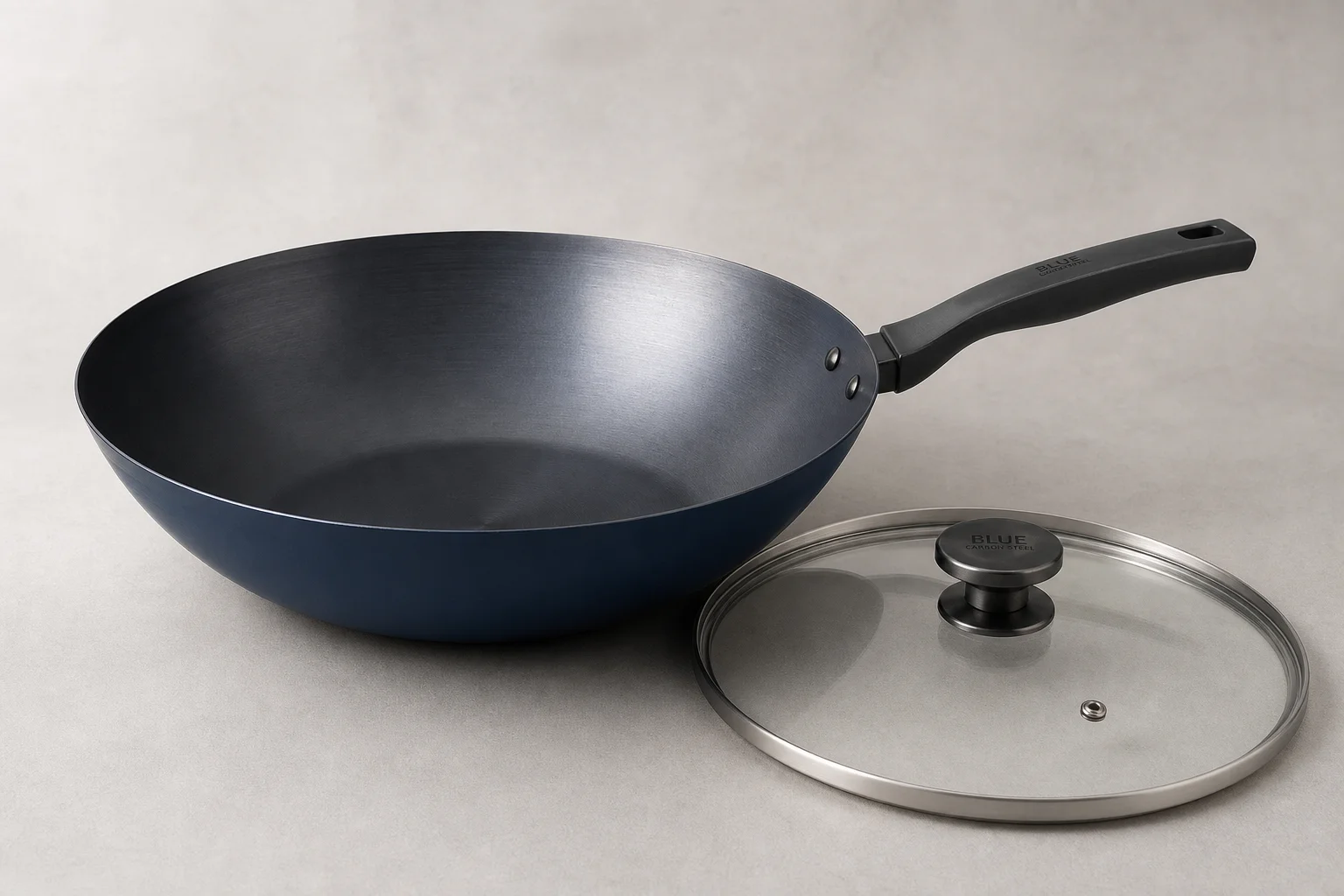 Yosukata 13.5-inch blue carbon steel wok with glass lid on neutral backdrop