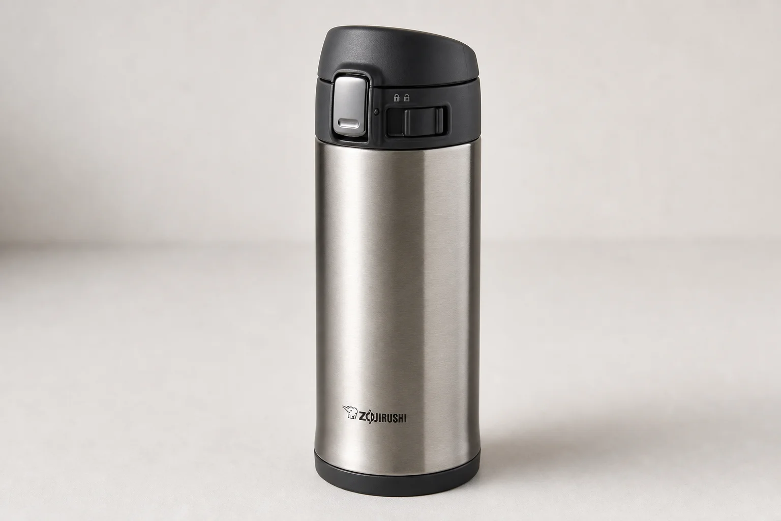 Nine insulated travel mugs arranged on concrete surface in various styles and colors